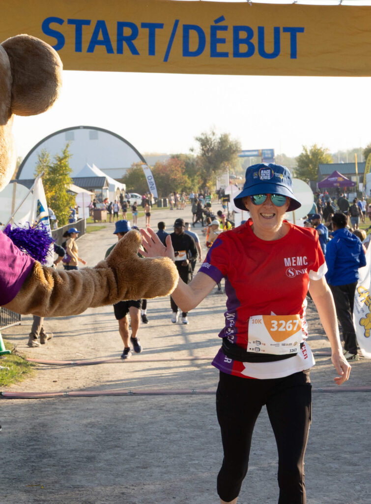 Participant giving CHEO bear a high five while running.