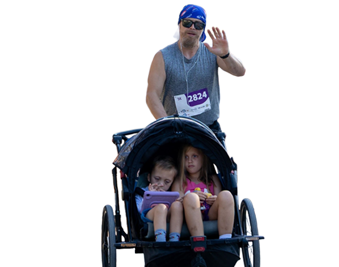 Dad pushing his children in a chariot.
