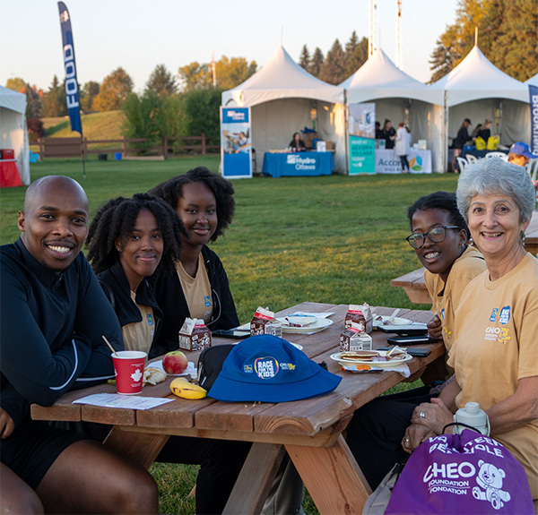 Volunteers and participants smiling, seated at a picnic table.